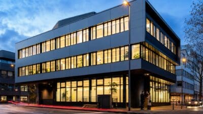 Modernes mehrstöckiges Bürogebäude mit vielen beleuchteten Fenstern bei Abenddämmerung