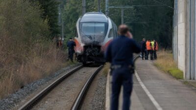 Verschmutzter Zug steht auf Gleisen mit Einsatzkräften und Polizisten am Unfallort