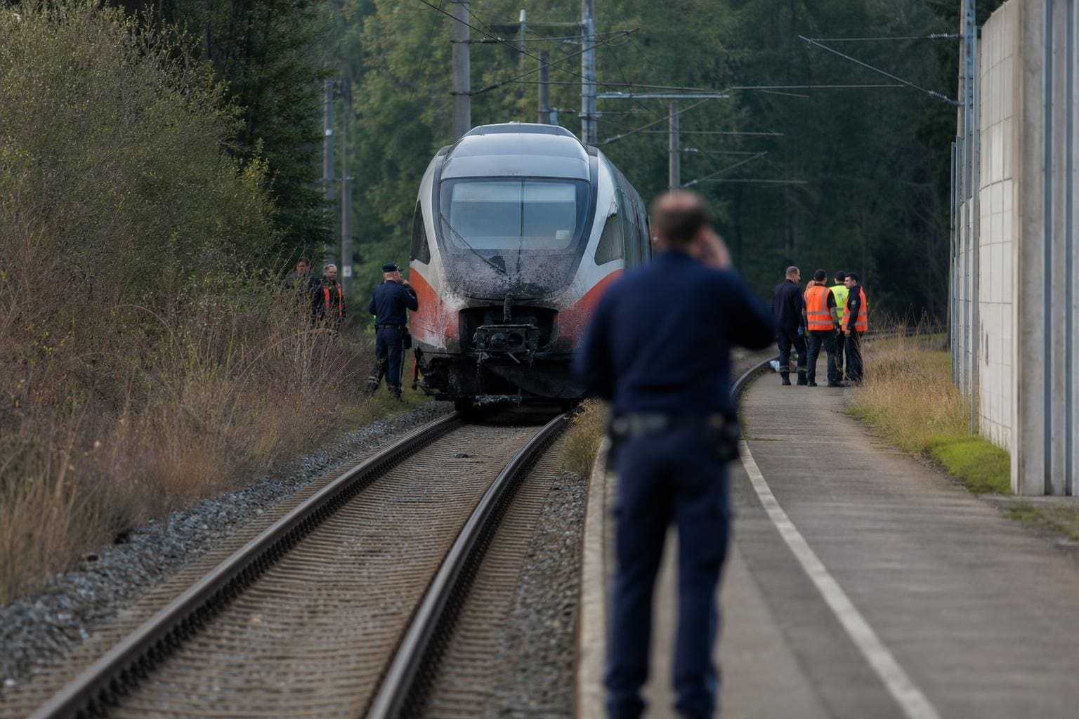 Verschmutzter Zug steht auf Gleisen mit Einsatzkräften und Polizisten am Unfallort