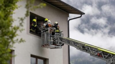 Feuerwehrleute auf einer Drehleiterplattform retten eine verletzte Person durch ein Fenster
