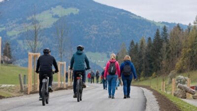Zwei Radfahrer und zwei Frauen auf einem neuen Weg vor Bergen
