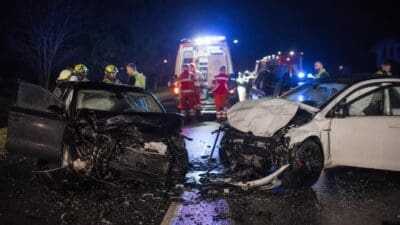 Zwei stark beschädigte Autos nach Frontalzusammenstoß bei Nacht mit Einsatzkräften