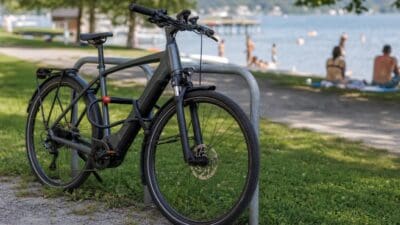 Dunkles E-Bike mit zwei Schlössern an einem Fahrradständer am Seeufer gesichert