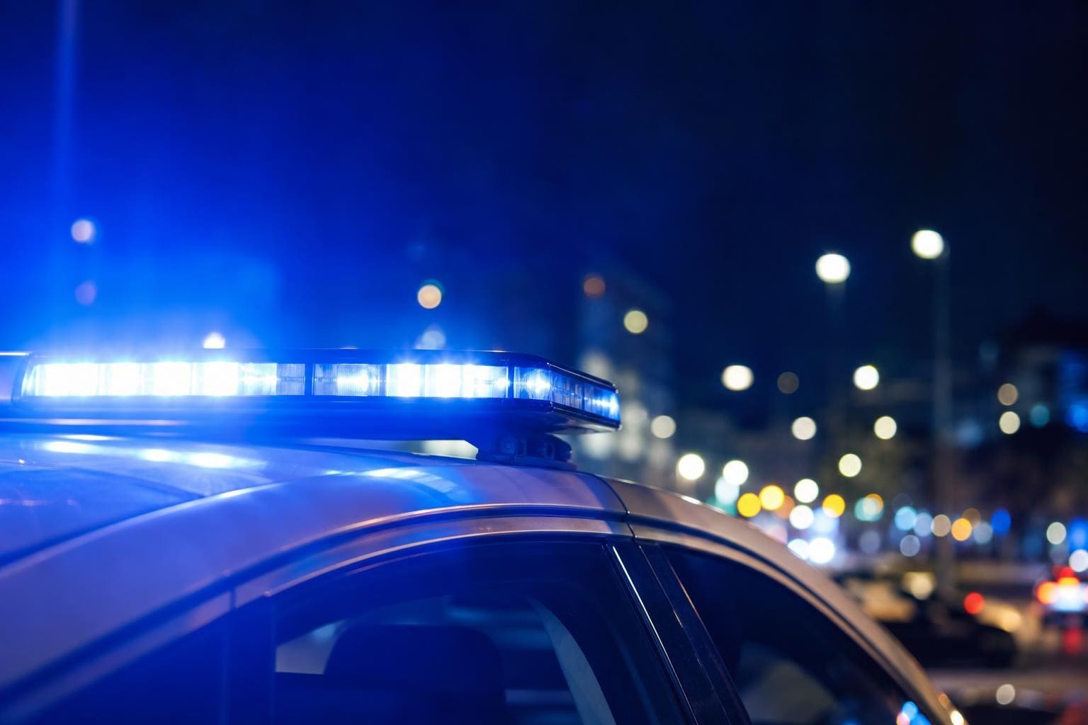 Blaulicht auf dem Dach eines Polizeiwagens bei Nacht in der Stadt
