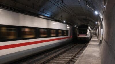 Weißer Hochgeschwindigkeitszug mit rotem Streifen fährt durch einen Tunnel.
