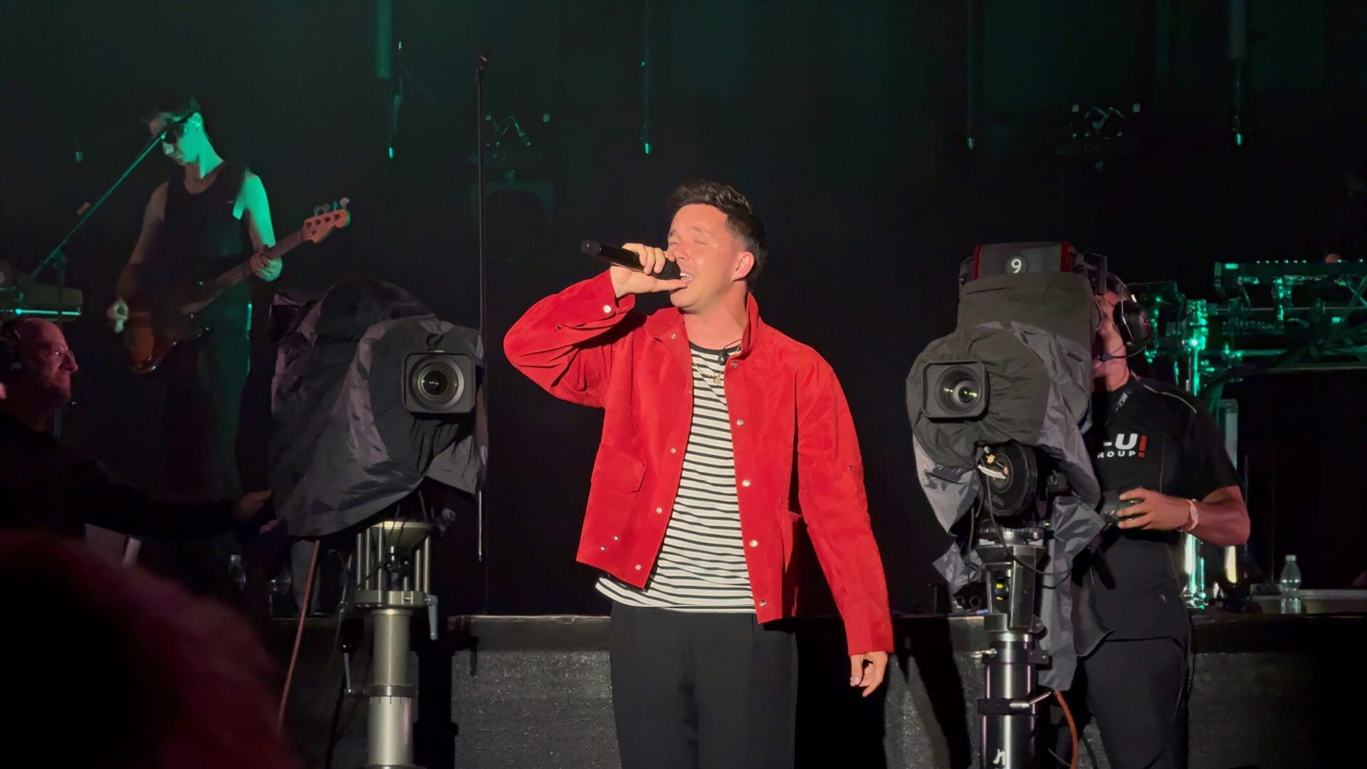 Sänger in roter Jacke singt mit geschlossenen Augen auf der Bühne beim Donauinselfest