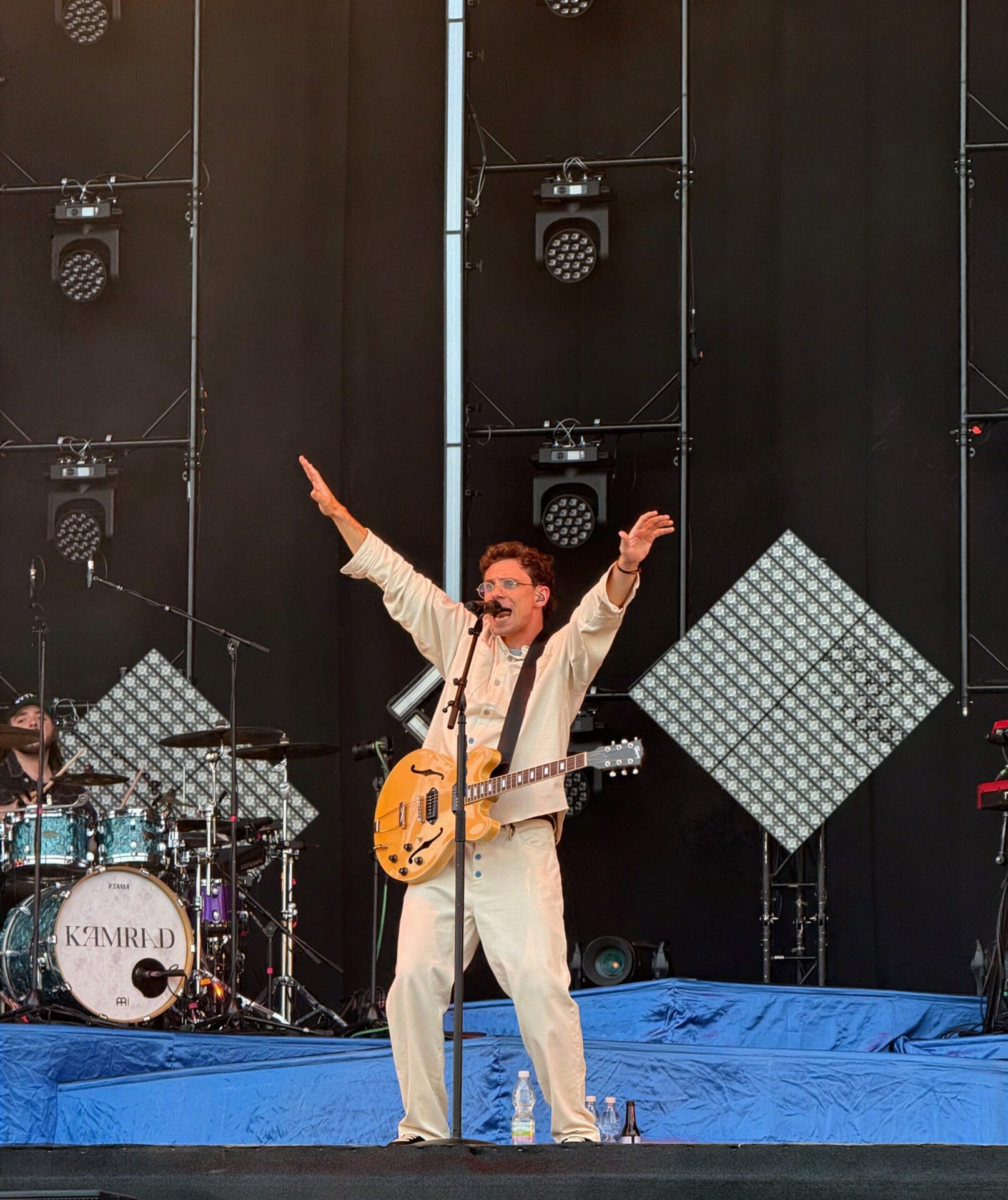 Musiker KAMRAD mit erhobenen Armen und Gitarre auf der Festivalbühne beim Donauinselfest
