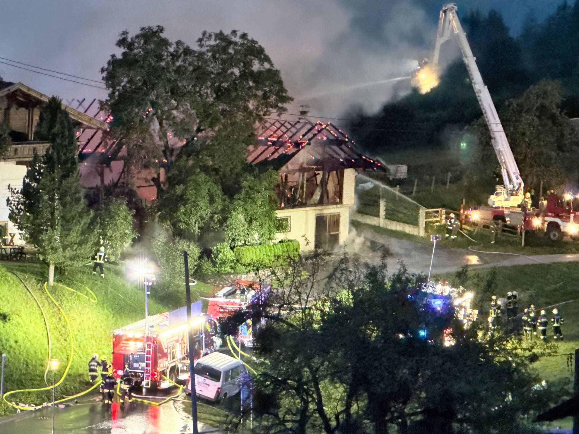 Feuerwehr löscht mit Drehleiter den Vollbrand eines Wirtschaftsgebäudes in Irschen bei Nacht.