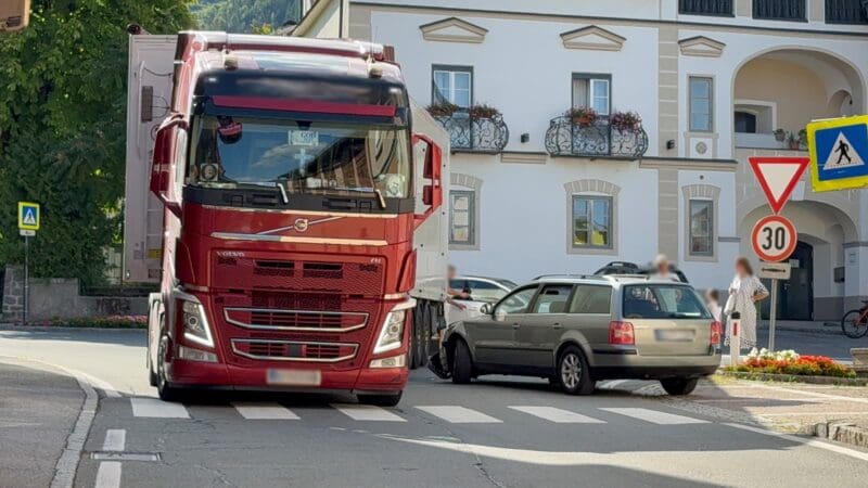 Roter Volvo Lkw und grauer Kombi nach Kollision auf Straße in Greifenburg
