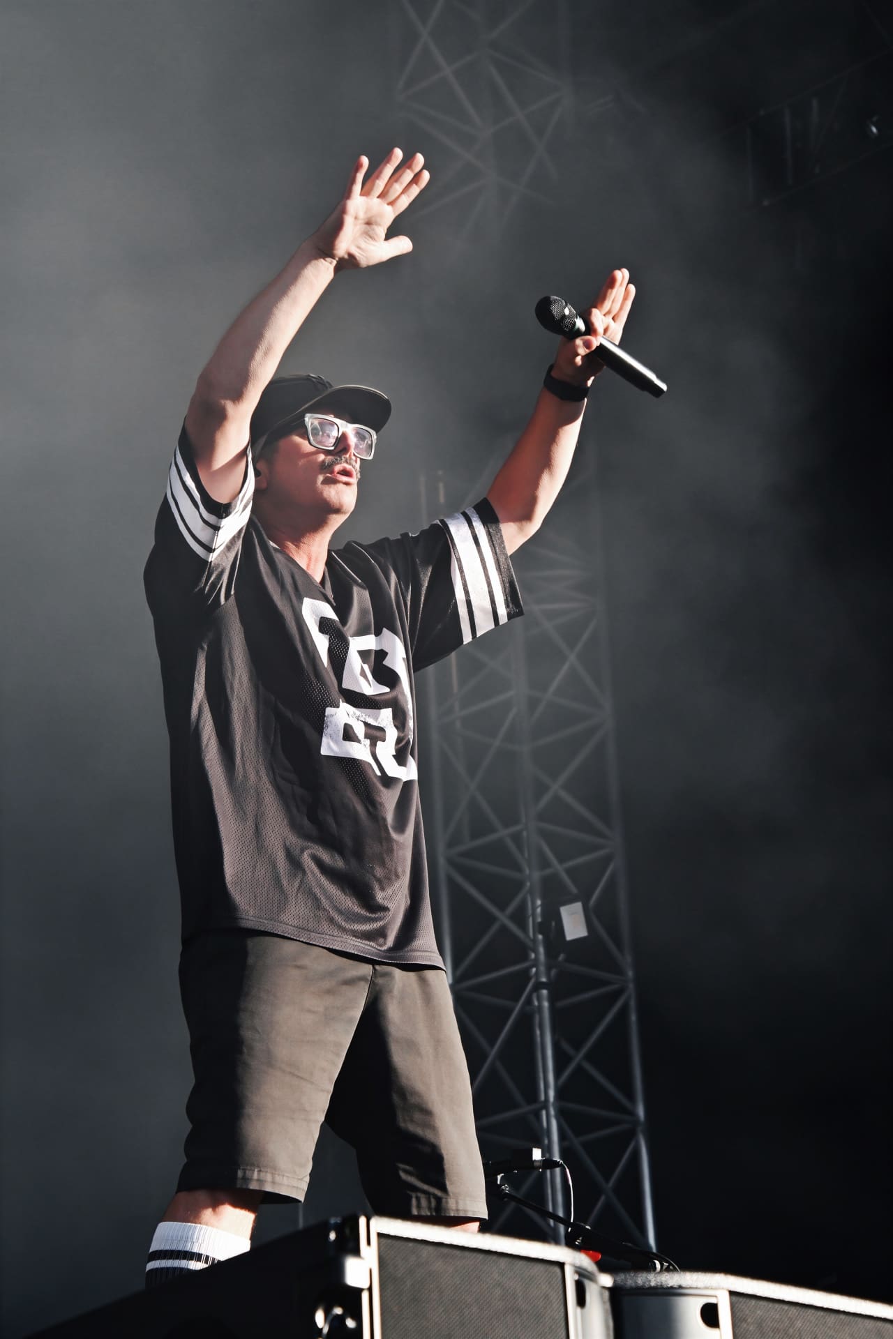 Ein Sänger mit Cap, Sonnenbrille und EC-Trikot hebt auf der Bühne eine Hand.
