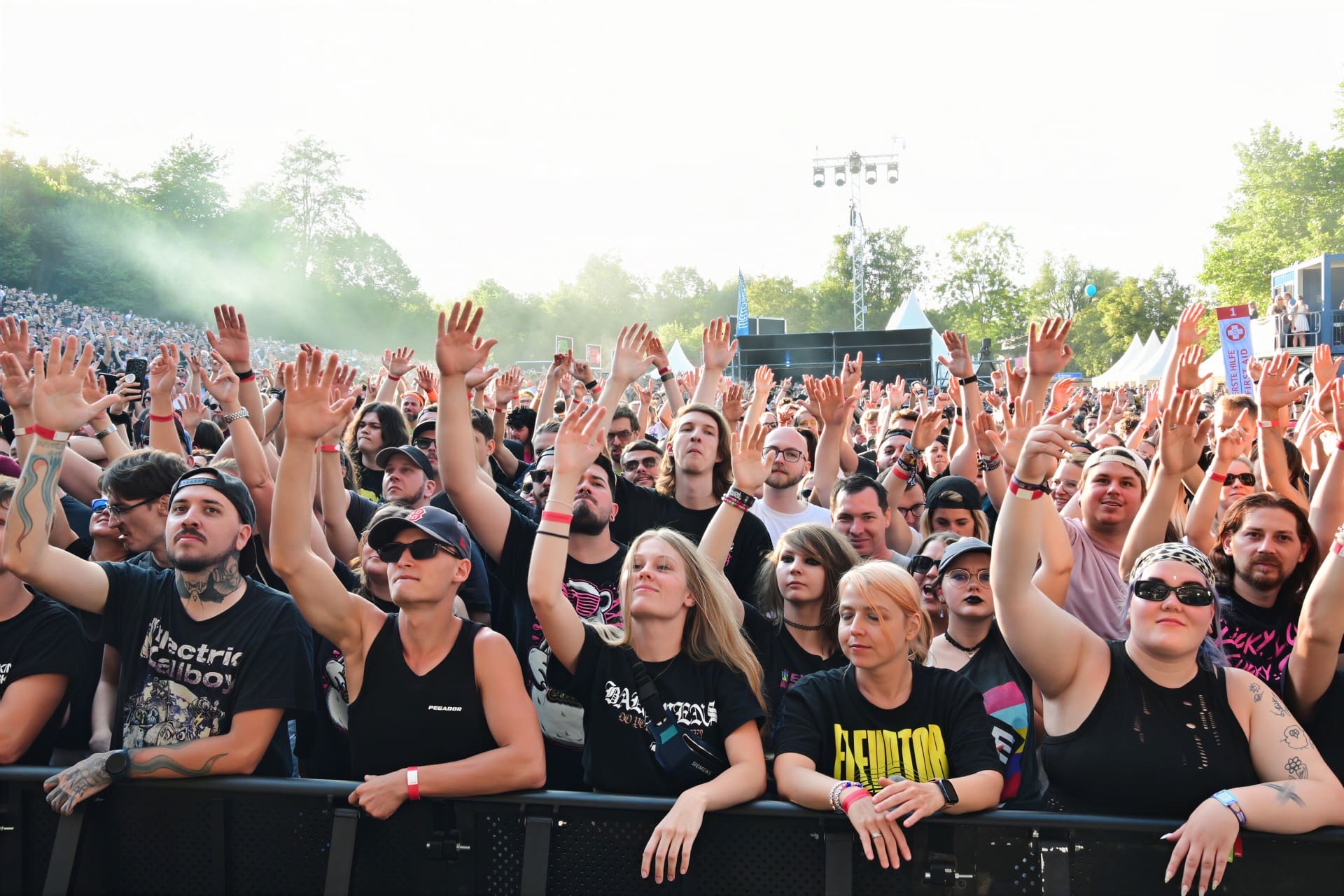 Fans mit erhobenen Händen stehen vor der Bühne beim Electric Callboy Konzert.