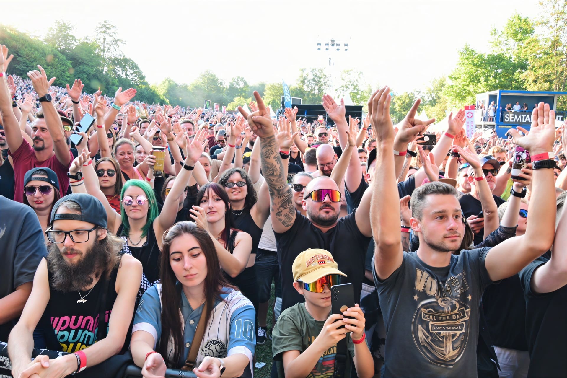 Dichte Menschenmenge bei einem Open-Air-Konzert hebt begeistert die Arme vor der Bühne.