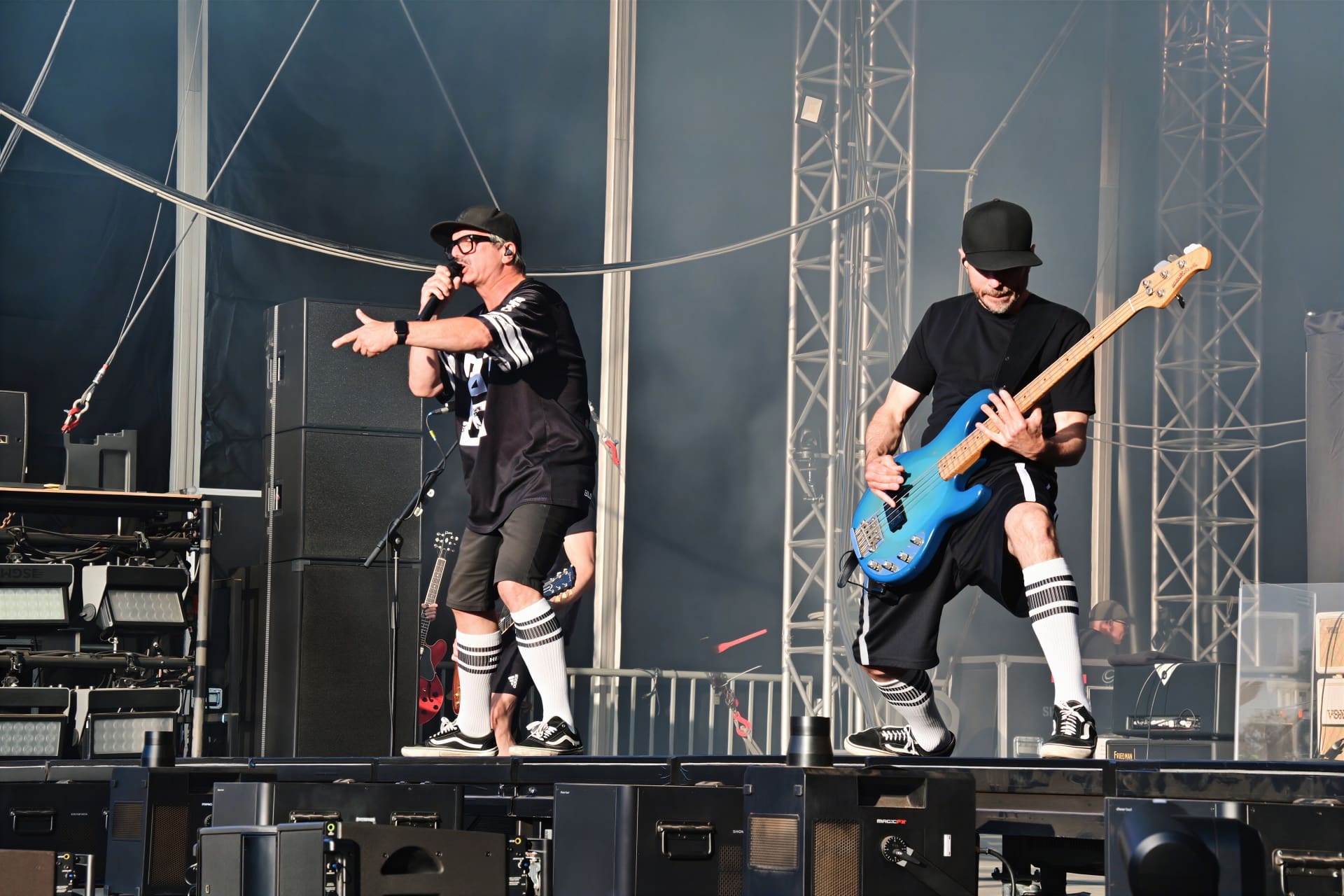 Zwei Musiker von Electric Callboy auf der Bühne, einer singt und zeigt, der andere spielt Bass