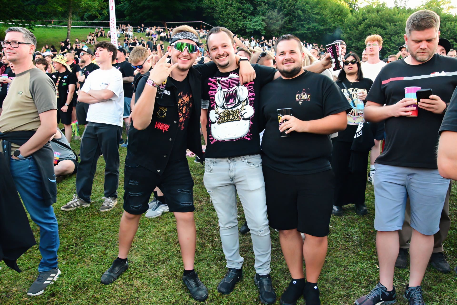 Gruppe junger Männer posiert vor großer Menschenmenge auf grüner Wiese beim Electric Callboy Konzert