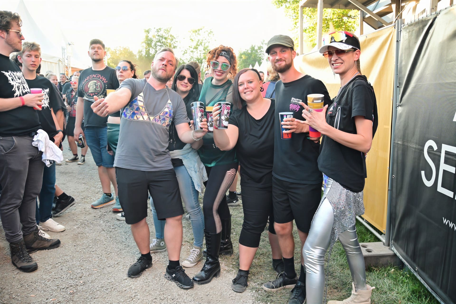 Gruppe junger Erwachsener posiert mit bunten Bechern beim Konzert auf der Schlosswiese in Moosburg