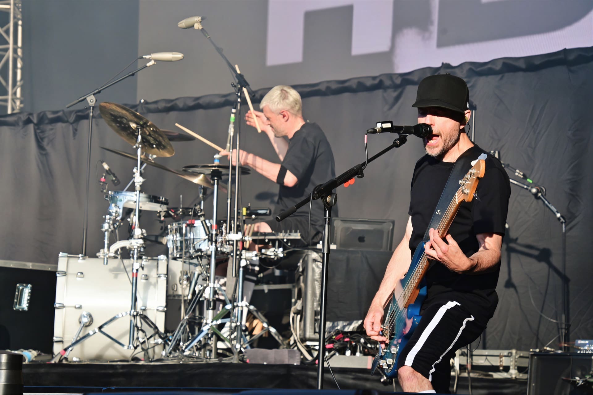 Bassist und Sänger von Electric Callboy auf der Bühne mit Schlagzeuger im Hintergrund
