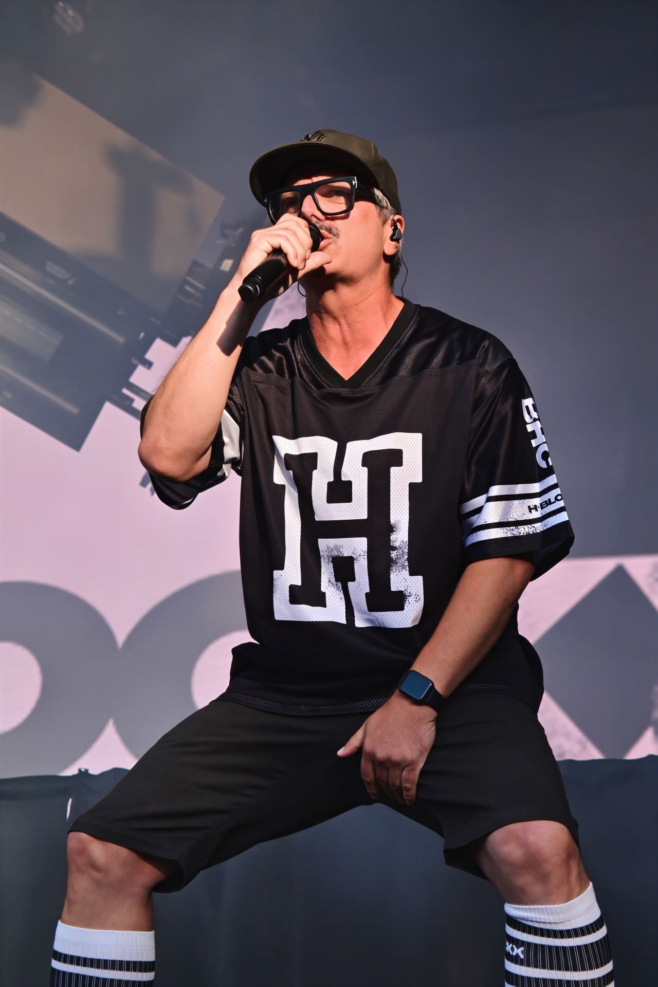 Sänger von H-Blockx mit Brille und Cap singt in ein Mikrofon auf der Bühne