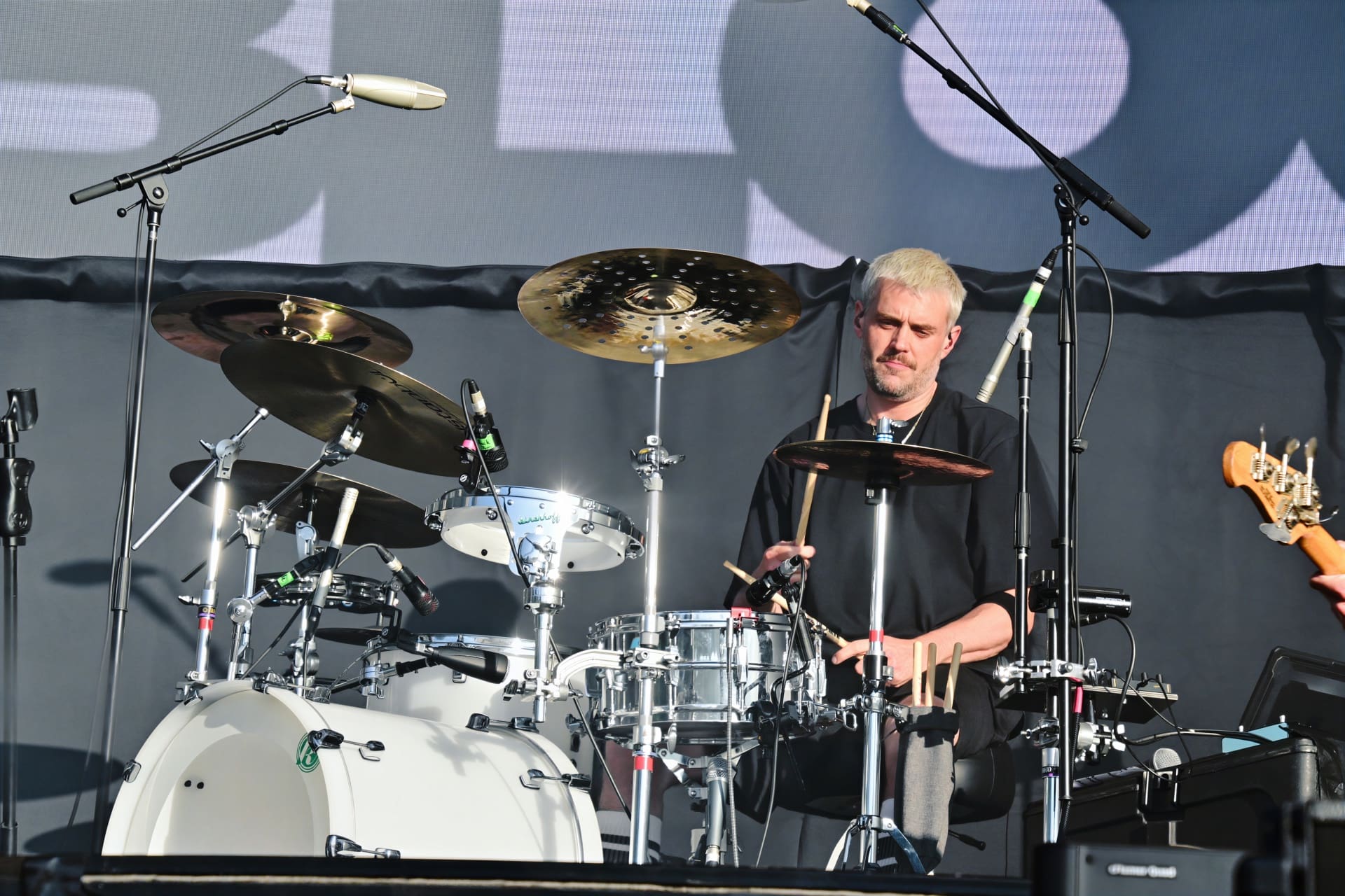 Schlagzeuger mit kurzen blonden Haaren und Bart spielt am Drumset auf der Bühne.