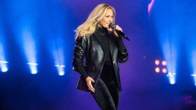 Helene Fischer singt auf der Bühne mit einem Mikrofon in der Hand unter blauen Scheinwerfern