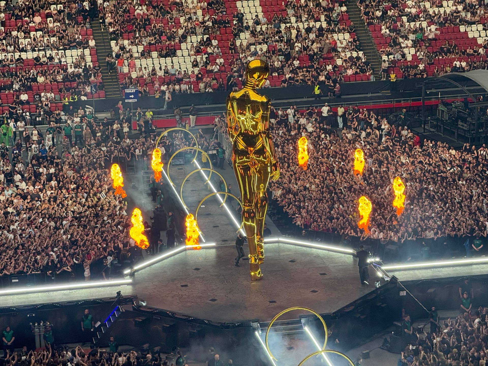 Eine große goldene Statue steht auf der Bühne eines Konzerts vor einer großen Menschenmenge.