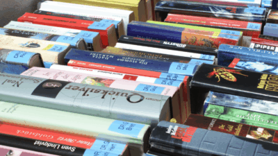 Nahaufnahme zahlreicher gestapelter Bücher mit bunten Buchrücken in einer Bibliothek