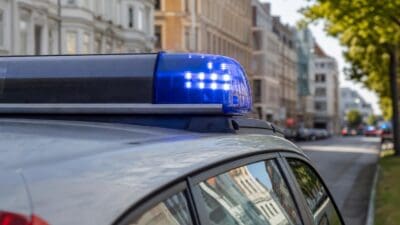 Nahaufnahme des blauen Blaulichts auf dem Dach eines Polizeifahrzeugs vor städtischen Gebäuden