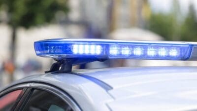 Nahaufnahme eines leuchtenden blauen Blaulichts auf dem Dach eines silbernen Polizeifahrzeugs