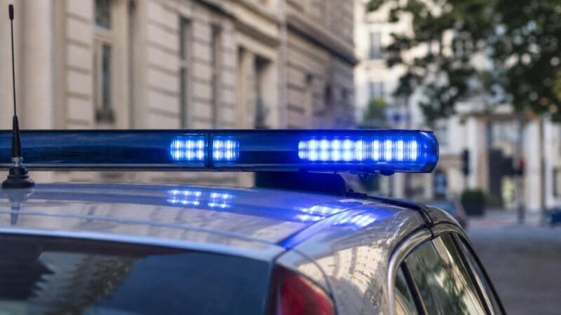 Blaues Blaulicht leuchtet auf dem Dach eines Polizeifahrzeugs vor einem Gebäude