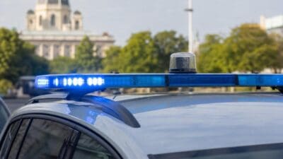 Nahaufnahme des blauen Blaulichts auf dem Dach eines Polizeifahrzeugs vor einem unscharfen Gebäude