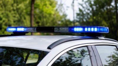 Blaues Blaulicht leuchtet auf dem Dach eines weißen Polizeifahrzeugs.