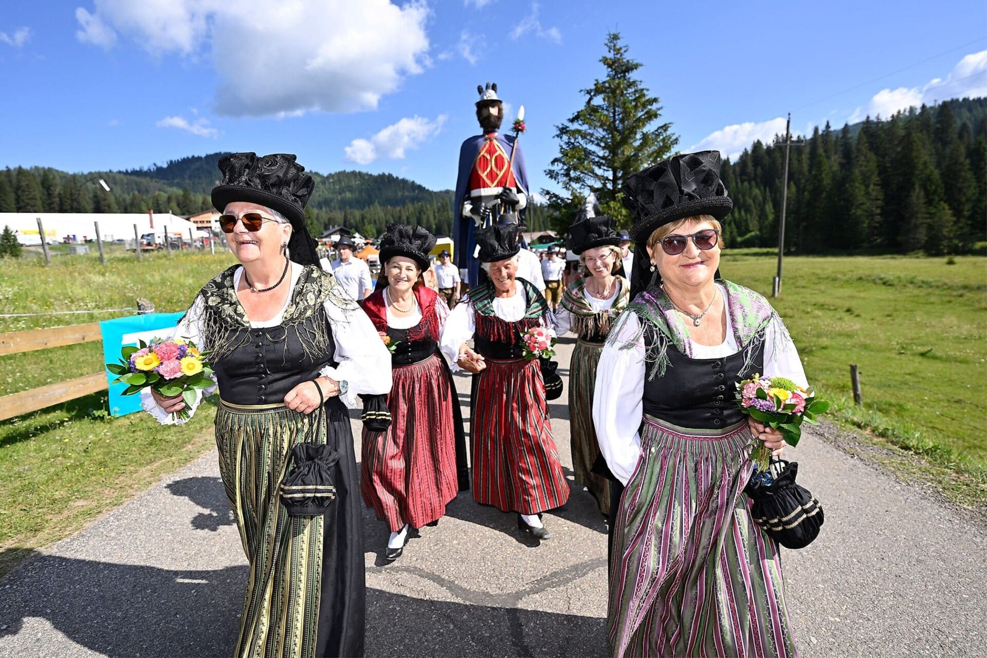 Frauen in traditionellen Trachten mit Blumensträußen beim Holzstraßenkirchtag auf der Flattnitz
