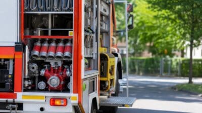 Heck eines Feuerwehrfahrzeugs mit geöffneten Fächern, roten Flaschen und einer Pumpe