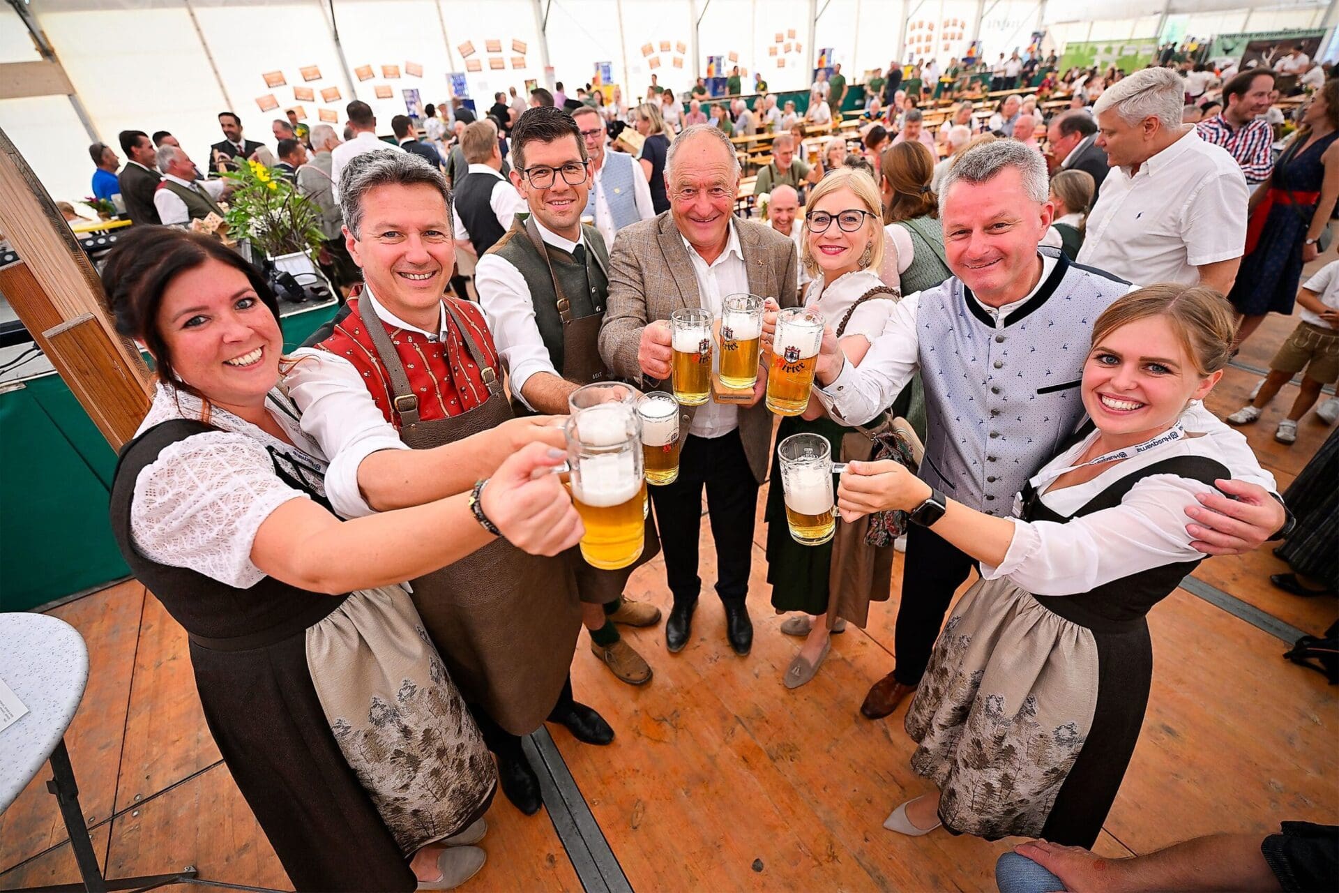 Gruppe in Tracht stößt mit Bierkrügen in einem Festzelt an