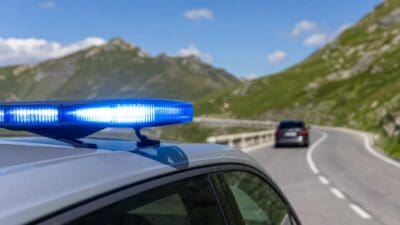Polizeiauto mit leuchtendem Blaulicht auf einer kurvigen Straße in den Bergen