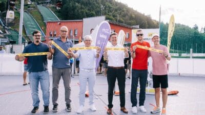 Fünf Männer halten gelbes Villach-Band auf dem Spielfeld der Alpen Arena