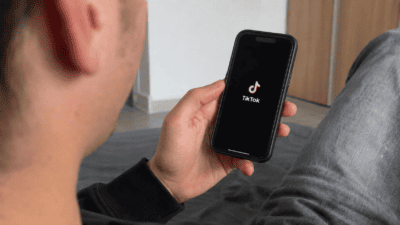 Ein Mann hält ein Smartphone mit dem TikTok-Logo auf dem Display in der Hand