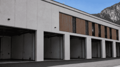 Modernes Gebäude mit mehreren offenen Fahrzeughallen und Bergen im Hintergrund