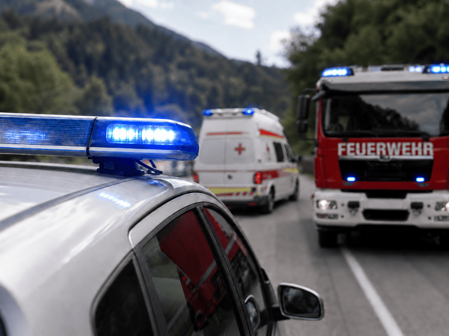 Polizeifahrzeug mit Blaulicht im Vordergrund vor Feuerwehr und Rettungswagen auf Bergstraße