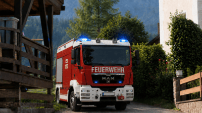 Rotes Feuerwehrfahrzeug mit blauem Blaulicht vor alpiner Berglandschaft