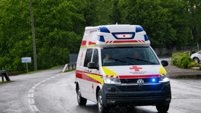 Weißer Rettungswagen des Österreichischen Roten Kreuzes fährt bei Regen auf nasser Straße