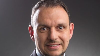 Porträt von Martin Grubhofer im dunklen Anzug vor grauem Hintergrund