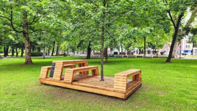 Hölzerner Chillout-Spot mit Sitzbänken auf einer Wiese im Stadtpark