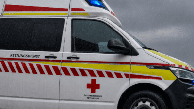 Weißer Rettungswagen des Österreichischen Roten Kreuzes mit rotem Kreuz und Streifen im Regen
