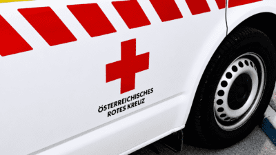 Seite eines weißen Rettungsfahrzeugs mit rotem Kreuz und gelb-roten Streifen des Österreichischen Roten Kreuzes