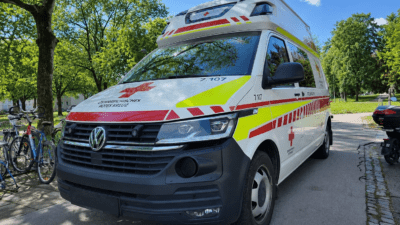 Weißer VW-Transporter des Österreichischen Roten Kreuzes mit roten Kreuzen im Park