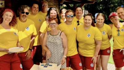 Gruppe von Wasserrettern in gelben T-Shirts steht um eine Torte bei der Einsatzstelle.