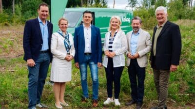 Sechs Personen stehen vor einem grünen Van in einer Waldlichtung