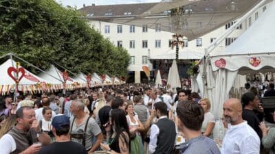 Viele Menschen in Tracht stehen vor weißen Zelten auf dem Villacher Kirchtag