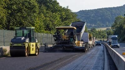 Gelbe Straßenwalze und Asphaltfertiger bei Bauarbeiten auf der Autobahn bei Velden-Ost