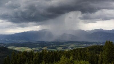 Dunkle Gewitterwolken mit Starkregen über einem grünen Tal in Kärnten